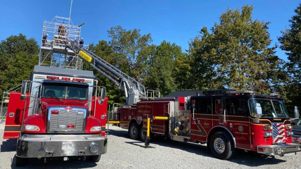 Campbellsville Fire Department ladder truck with firefighters training on an elevated platform beside a fire engine.