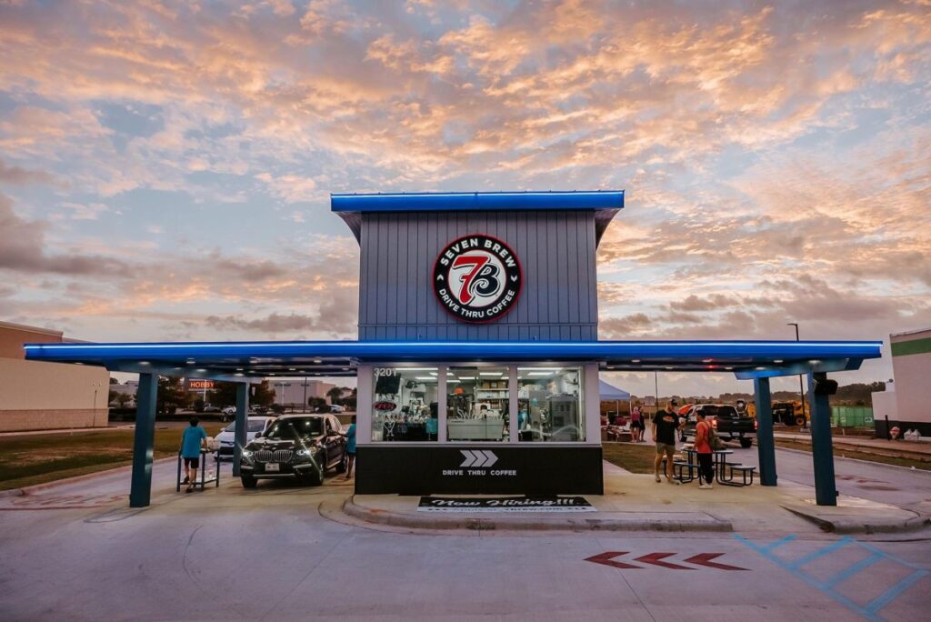 Model image of a completed 7 Brew Coffee drive-thru stand, showing the small building with dual drive-thru lanes and no indoor seating.